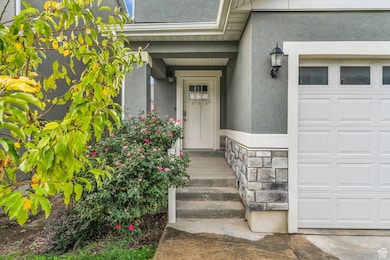 Property entrance featuring a garage, stone siding, and stucco siding