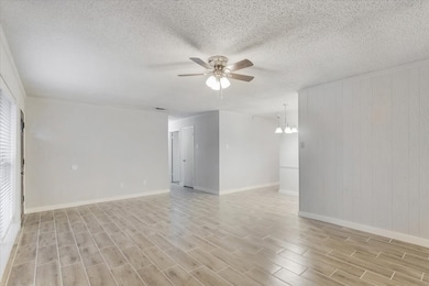 Spare room featuring ceiling fan, wood finish floors, a textured ceiling, and a chandelier
