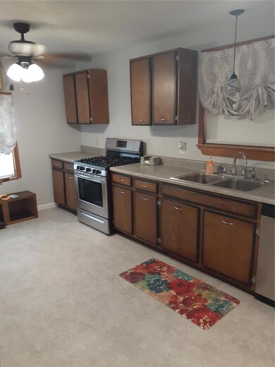Kitchen featuring ceiling fan, a sink, dark brown cabinets, and stainless steel gas range