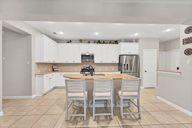 This spacious kitchen features high ceilings, white stained wood cabinets, granite countertops, SS appliances, modern tile backsplash, recessed lighting, extended counter space, granite kitchen island with double sink and space for breakfast bar, and a walk-in pantry all overlooking your huge family room.