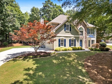 View of front of property featuring concrete driveway, a chimney, and a front yard