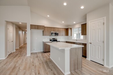 Kitchen featuring light countertops, lofted ceiling, recessed lighting, a center island, and appliances with stainless steel finishes