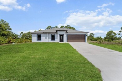 Prairie-style house with concrete driveway, stucco siding, an attached garage, and a front yard