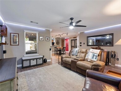 Living area featuring a ceiling fan, wood finished floors, baseboards, track lighting, and ornamental molding