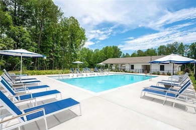 Community pool with a patio area and view of wooded area