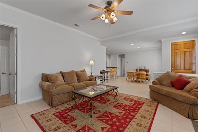 Tiled living room with ceiling fan, crown molding