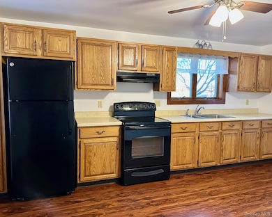 Kitchen featuring black appliances, light countertops, dark wood finished floors, under cabinet range hood, and a ceiling fan