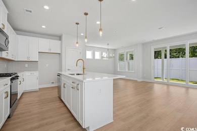 Kitchen featuring appliances with stainless steel finishes, light wood finished floors, a chandelier, light countertops, and recessed lighting