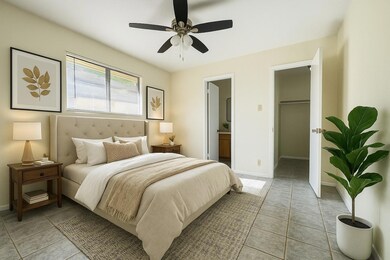 Bedroom featuring light tile patterned flooring, ceiling fan, a spacious closet, and connected bathroom