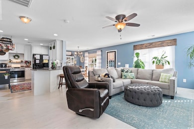 Living room with ceiling fan with notable chandeli