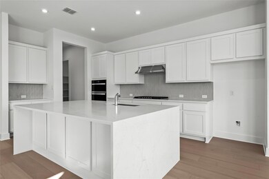 Kitchen with range hood, black stovetop, a center