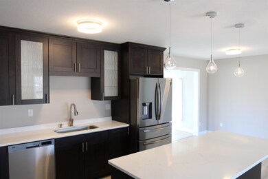 Kitchen featuring appliances with stainless steel finishes decorative light fixtures, dark brown cabinetry, and a center island