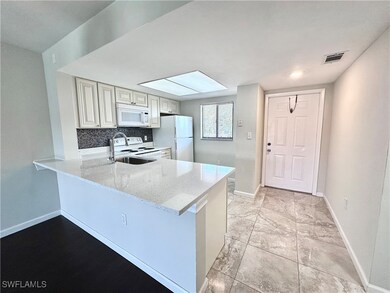 Kitchen with white appliances, baseboards, a penin
