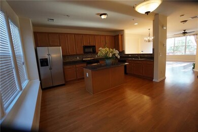 Kitchen featuring stainless steel fridge with ice dispenser, black microwave, stove, decorative backsplash, and wood finished floors