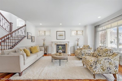 Living area featuring a high end fireplace, wainscoting, crown molding, stairway, and a decorative wall