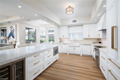 Kitchen with stainless steel stove, a tray ceiling, plenty of natural light, wine cooler, and recessed lighting