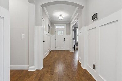 Entrance foyer featuring crown molding, arched walkways, and dark wood-style floors