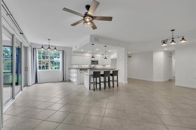 Kitchen featuring open floor plan, white cabinetry, a kitchen bar, pendant lighting, and a center island