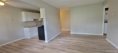 Kitchen featuring white cabinetry, light wood-style flooring, light stone counters, and gas stove
