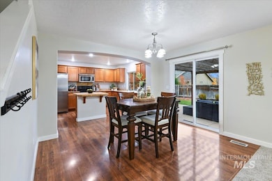 Dining room featuring dark wood finished floors, a textured ceiling, arched walkways, and a chandelier