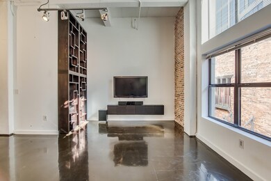 Exposed brick and 15 ft. ceilings in this loft-style condo. Custom bookcase, TV and sound system included.