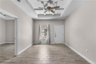 Entryway with a tray ceiling, ceiling fan, wood finished floors, and baseboards