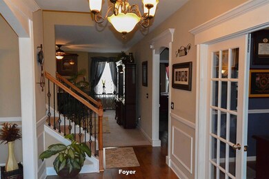 Inviting Entry foyer with hardwood flooring, cased opening going into the connected rooms, wainscoting, side lights on each side of the entry door, and upgraded metal balusters and oak handrails on the open section of the stair case.