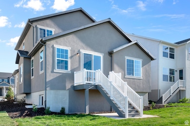 Rear view of house featuring stairs, stucco siding, and a yard