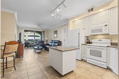 Kitchen with crown molding, white appliances, a center island, white cabinets, and light tile patterned floors
