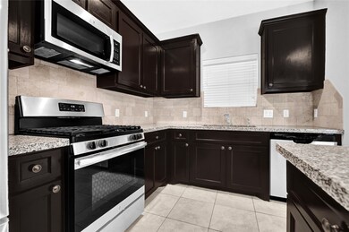 The granite countertops provide a nice contrast to the sleek dark cabinets