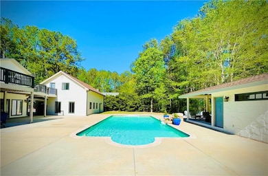 Swimming pool with a patio and view of wooded area