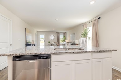 Kitchen featuring dark wood-style flooring, white cabinetry, stainless steel dishwasher, light stone countertops, and recessed lighting