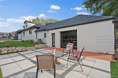 Rear view of house featuring stucco siding, a lawn, a patio area, stone siding, and roof with shingles