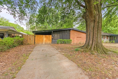 View of front of property featuring a gate, driveway, and brick siding
