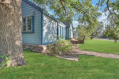 View of side of property with a lawn, large trees, and walkway in Sayre, OK