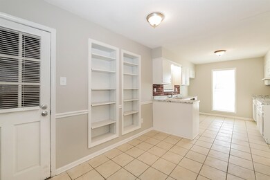 Kitchen with built in features, white cabinetry, light tile patterned flooring, and light countertops