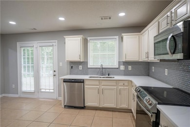 Kitchen with stainless steel appliances, tasteful backsplash, light tile patterned floors, recessed lighting, and light stone countertops