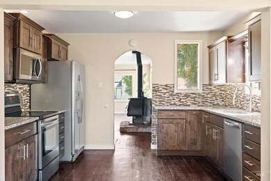 Kitchen with appliances with stainless steel finishes, a wood stove, healthy amount of natural light, and dark wood-style floors