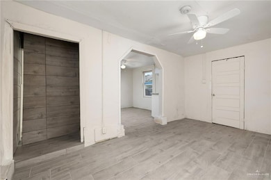 Spare room with a ceiling fan, light wood-style flooring, and arched walkways