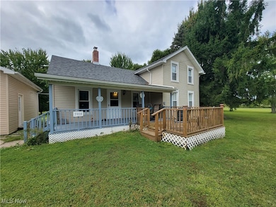 Rear view of house with a lawn, a wooden deck, and a chimney