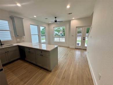 Kitchen featuring gray cabinets, a sink, light wo