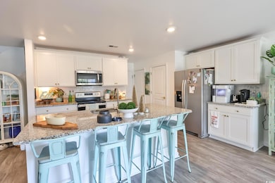 Kitchen with tasteful backsplash, stainless steel appliances, white cabinets, a breakfast bar, and recessed lighting
