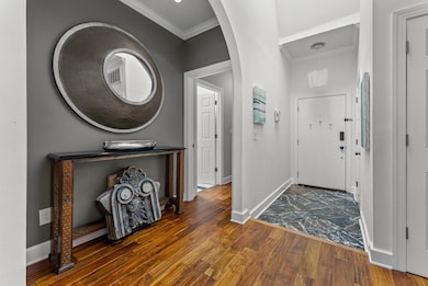Foyer featuring crown molding and dark hardwood/ wood-style flooring