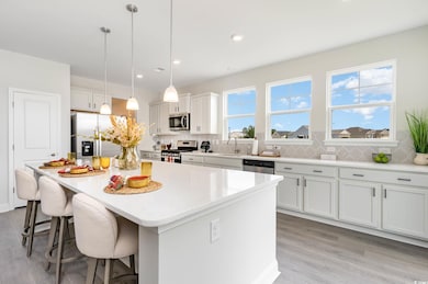 Kitchen with stainless steel appliances, a kitchen breakfast bar, light wood-style floors, a center island, and decorative backsplash