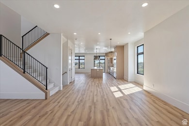 Unfurnished living room with recessed lighting, light wood-style floors, and stairway
