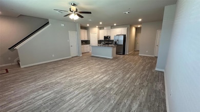 Kitchen with white cabinetry, a kitchen island, stainless steel appliances, backsplash, and ceiling fan