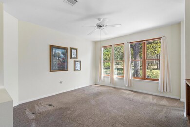 Carpeted spare room featuring ceiling fan and baseboards