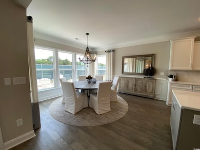 Dining space featuring ornamental molding, a chandelier, and dark wood-type flooring