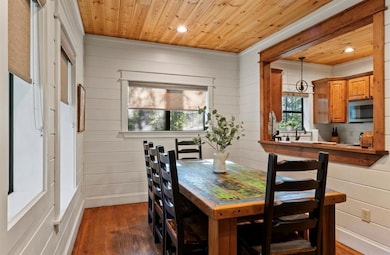 Dining area with wood walls, dark wood-style floors, wooden ceiling, and recessed lighting