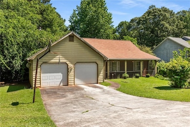 View of front of house featuring an attached garage, concrete driveway, a front yard, and covered porch